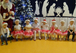 Dzieci recytują wierszyk, w tlę dekoracja świąteczna.